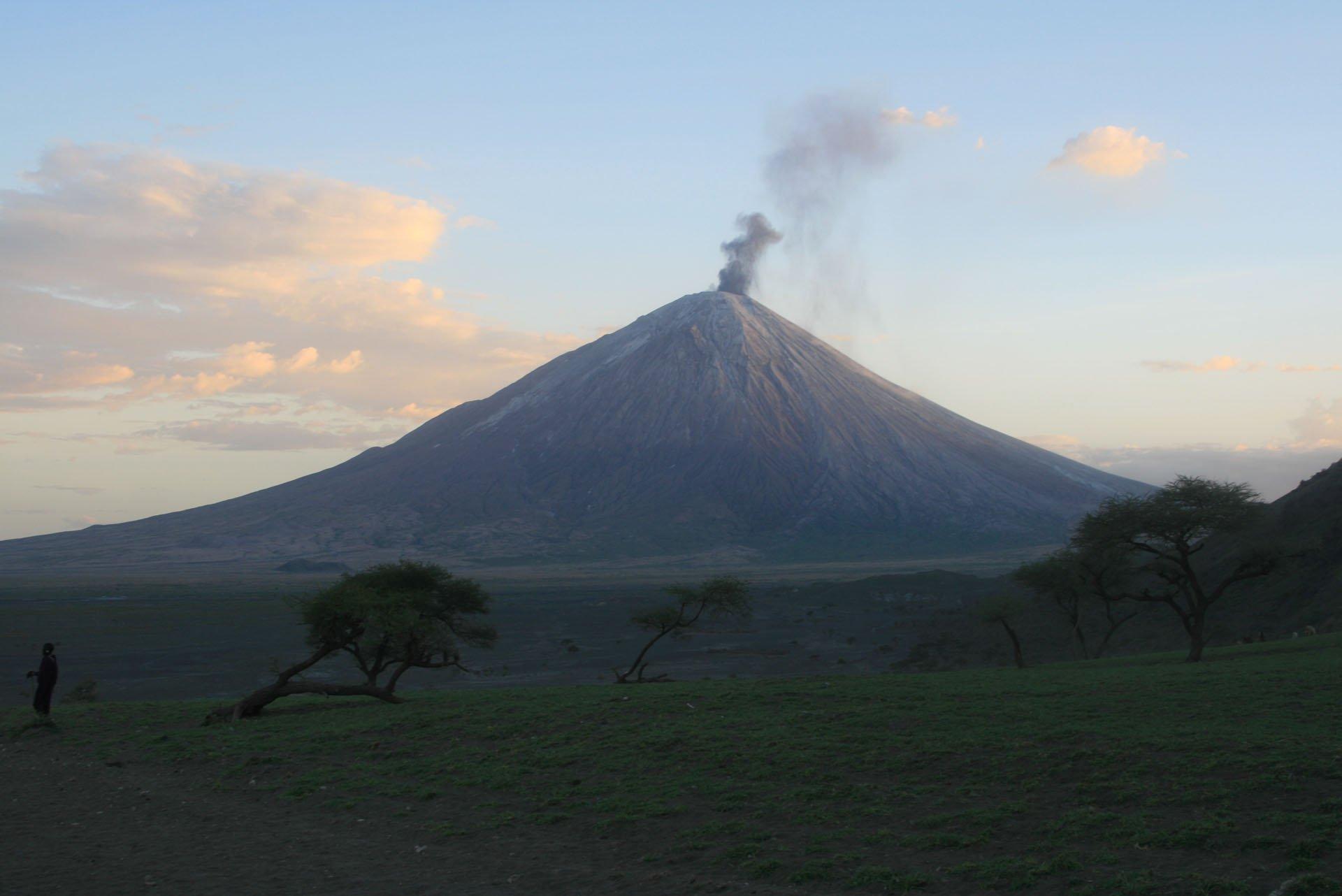 Vast African landscape at Lake Natron in Tanzania's Rift Valley with active volcano in background